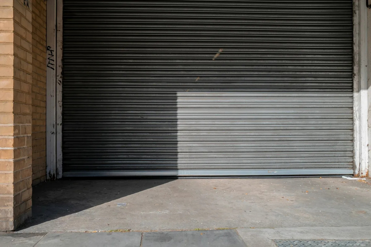 Warehouse roll-up door raised halfway over a concrete floor