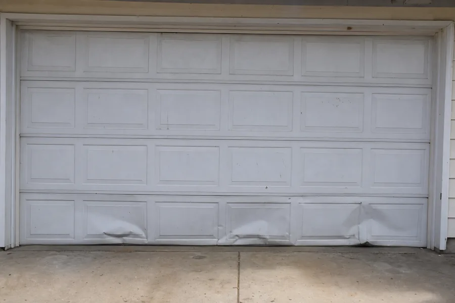 Dented panel sections on an older garage door in Pueblo, CO