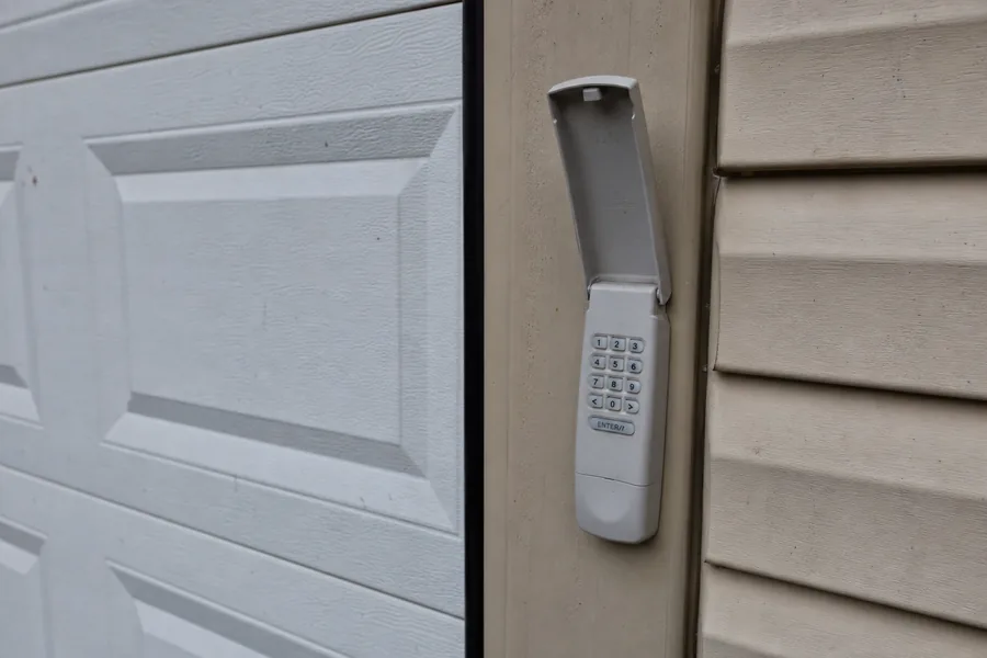 Keypad beside a garage door in bright afternoon sun